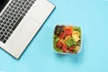 Healthy business lunch in the office, salad for snack on blue table. Top view with copy space. Concept proper nutrition. Take away