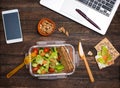 Healthy business lunch at workplace. Salad, salmon, avocado and bread crisps lunch box on working desk with laptop, smartphone Royalty Free Stock Photo