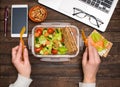 Healthy business lunch at workplace. Salad, salmon, avocado and bread crisps lunch box on working desk with laptop, smartphone, Royalty Free Stock Photo