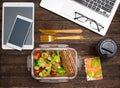 Healthy business lunch at workplace. Salad, salmon, avocado and bread crisps lunch box on working desk with laptop, smartphone, Royalty Free Stock Photo