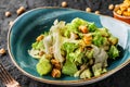 Healthy caesar salad with chickpeas, crackers, lettuce, cheese sauce in ceramic plate over dark background. Healthy food,