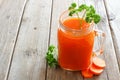 Healthy carrot juice in a mason jar with carrot slices over rustic wood