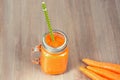 Healthy carrot smoothie in a jar with tube on wooden background Royalty Free Stock Photo