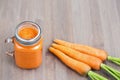 Healthy carrot smoothie in a mason jar with raw carrots on wooden background Royalty Free Stock Photo