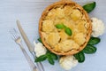 Healthy cauliflower pie decorated with fresh basil leaves and vintage silver knife and fork. Vegetarian cauliflower tart