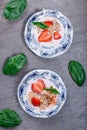 Healthy cereal with strawberries and yogurt decorate with mint in a ceramic bowls on wooden table. Granola, muesli