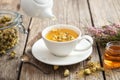 Healthy chamomile tea poured into white cup. Teapot, honey jar, heather bunch, jar of daisy herbs. Royalty Free Stock Photo