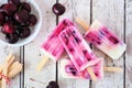 Healthy cherry yogurt popsicles table scene over rustic white wood Royalty Free Stock Photo