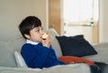 Healthy child eating red apple, School boy eating fresh fruit for his snack while watching TV, Portrait kid face eating food.