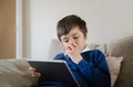 Healthy child eating red apple while watching cartoon on digital tablet, School boy bitting fresh fruit for his snack, Close up