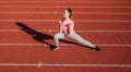 healthy child girl training dumbbells on stadium running track, power