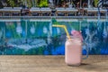 Healthy cold strawberry smoothie in glass mug on wooden table with swimming pool background on a sunny summer day, closeup, copy Royalty Free Stock Photo