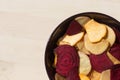Healthy colorful vegetable chips in purple bowl.