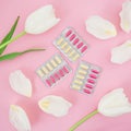 Healthy composition with vitamins pill and white flowers on pink background. Flat lay, top view.