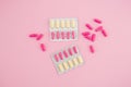 Healthy composition with vitamins pills on pink background. Flat lay, top view.