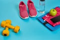 Healthy concept, diet plan with sport shoes and bottle of water and dumbbells on blue background, healthy food and Royalty Free Stock Photo