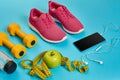 Healthy concept, diet plan with sport shoes and bottle of water and dumbbells on blue background, healthy food and Royalty Free Stock Photo