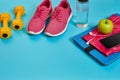 Healthy concept, diet plan with sport shoes and bottle of water and dumbbells on blue background, healthy food and Royalty Free Stock Photo