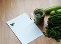 Blended green smoothie with ingredients on wooden table.