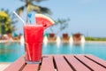 Healthy concept, Water melon smoothie on a wood table with swimming pool and blue sky background.