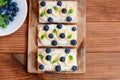 Homemade soft cheese, bananas and berries sandwiches. Healthy crisp bread with sweet toppings on wooden board. Top view