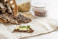 Healthy crispy snacks baked from linseed, oat flakes and various seeds, one with butter and parsley garnish on a light napkin and