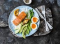 Healthy delicious balanced lunch - baked salmon, rice, asparagus, avocado and boiled egg on a dark background, top view Royalty Free Stock Photo