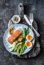 Healthy delicious balanced lunch - baked salmon, rice, asparagus, avocado and boiled egg on a dark background, top view Royalty Free Stock Photo