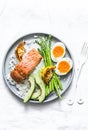 Healthy delicious balanced lunch - baked salmon, rice, asparagus, avocado and boiled egg on a light background, top view Royalty Free Stock Photo