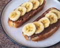 Healthy and delicious snack with peanut butter sandwiches and banana slices on a round plate, close-up Royalty Free Stock Photo