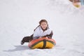 Healthy delightful little girl in ski suit riding on tube during snow tubing leisure activity on winter mountain alpine resort Royalty Free Stock Photo