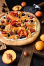 Healthy dessert. Fruit homemade pizza made with raw peaches, apricots, cherries, currants and ricotta cream on dark wooden Royalty Free Stock Photo