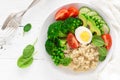 Healthy detox dish with egg, avocado, quinoa, spinach, fresh tomato, green peas and broccoli on white wooden background Royalty Free Stock Photo