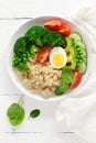 Healthy detox dish with egg, avocado, quinoa, spinach, fresh tomato, green peas and broccoli on white wooden background Royalty Free Stock Photo