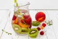 Healthy detox fruit infused flavored water. Summer refreshing homemade cocktail with fruits, thyme on wooden table. Clean eating