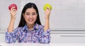 Healthy diet concept. smiling young woman holding green and red fresh apple in her kitchen looking camera Royalty Free Stock Photo