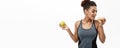 Healthy and diet concept - Beautiful sporty African American make a decision between donut and green apple. Isolated on Royalty Free Stock Photo