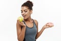 Healthy and diet concept - Beautiful sporty African American make a decision between donut and green apple. Isolated on Royalty Free Stock Photo