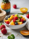 Healthy diet, light fresh fruit salad in a white bowl on a white background, strawberries and tropical fruits Royalty Free Stock Photo