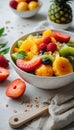 Healthy diet, light fresh fruit salad in a white bowl on a white background, strawberries and tropical fruits Royalty Free Stock Photo