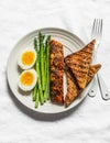 Healthy diet lunch - baked salmon, boiled soft eggs, asparagus and wholegrain bread on a light background, top view