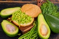 Healthy diet Mexican guacamole burger on the wooden board decorated with fresh dill. Vegetarian green sandwich on the black table Royalty Free Stock Photo