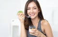 Healthy Diet And Nutrition. Portrait of happy beautiful young Asian woman eating natural yogurt at home and looking at camera. Royalty Free Stock Photo