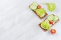 Healthy dietary breakfast of crisps rye flat toast with fresh vegetables - green salad, cucumber, tomato, cream cheese on white.
