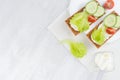 Healthy dietary breakfast of crisps rye flat toast with fresh vegetables - green salad, cucumber, tomato, cream cheese on white. Royalty Free Stock Photo