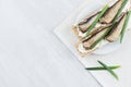 Healthy dietary breakfast of whole grain wheat crisps breads with anchovies, cream cheese, green onion sprout on white wood.