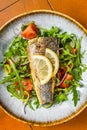 Healthy diner with sea bass fillet and vegetable salad, seabass fish. Orange background. Top view Royalty Free Stock Photo