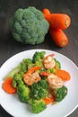 Healthy dish of prawn stir fried with broccoli and carrot served on white plate