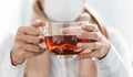 A healthy dose of natures medicine. a businesswoman having a glass of herbal tea in a modern office.