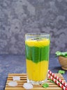A healthy drink, a three-layer smoothie with fresh spinach and ripe mango in a tall glass